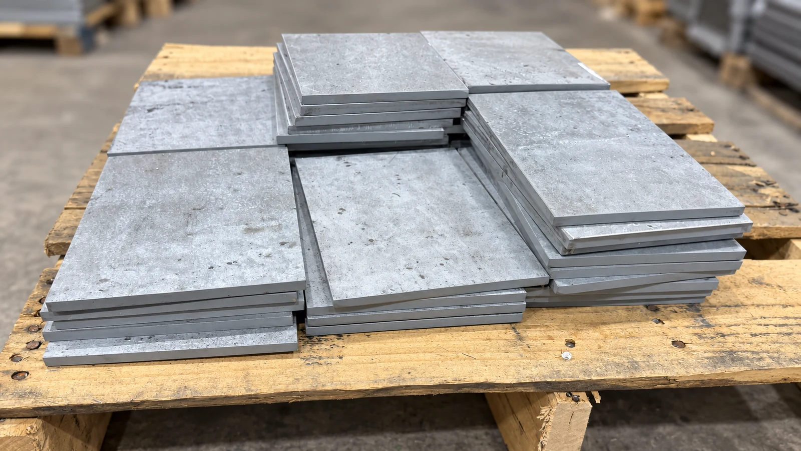 Hot-dip galvanized steel plates from a Rapid CNC Parts project, stacked on a pallet.